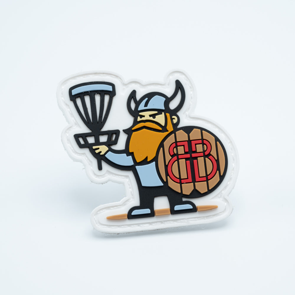 Disc golf patch in pvc with a viking holding a disc golf basket in one hand and a shield in the other hand