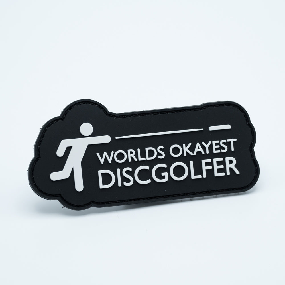 Discgolf patch in pvc with a character throwing a discgolf disc and the text Worlds Okayest Discgolfer