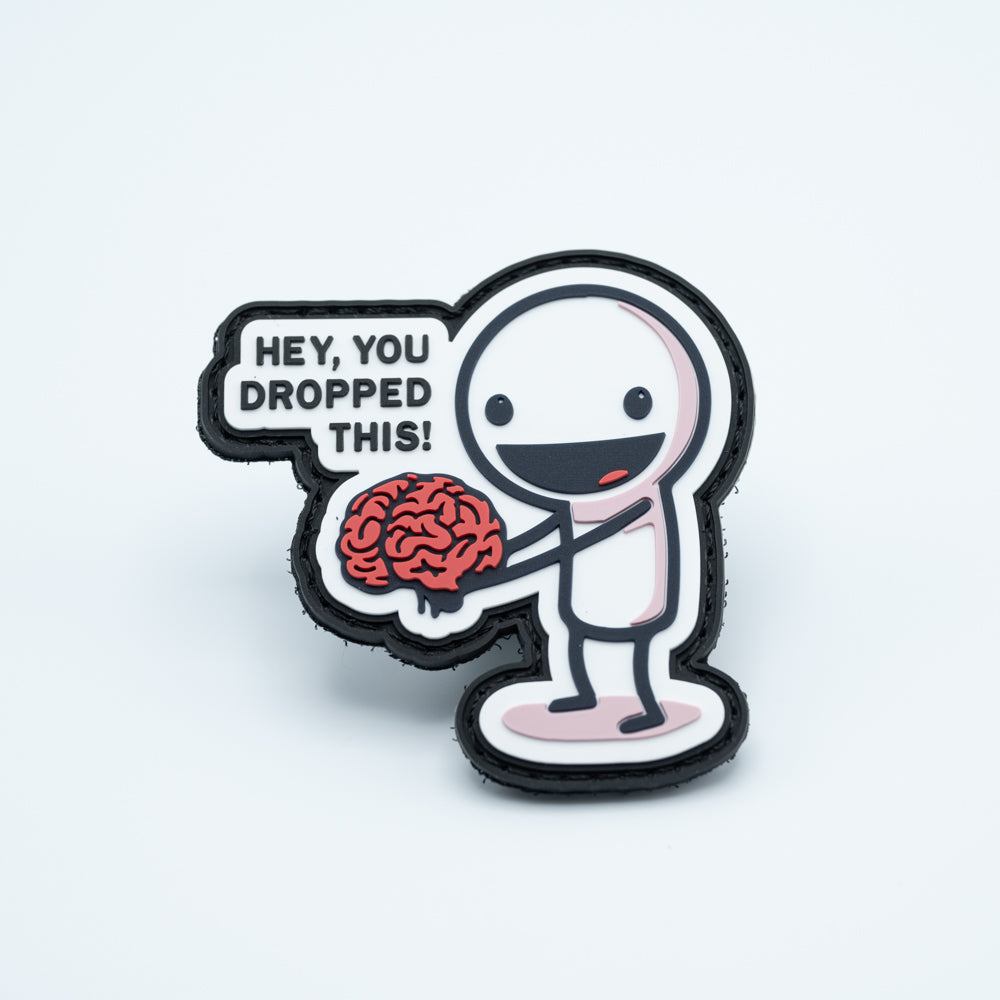 PVC Disc golf patch with a character holding a brain and the text HEY YOU DROPPED THIS!