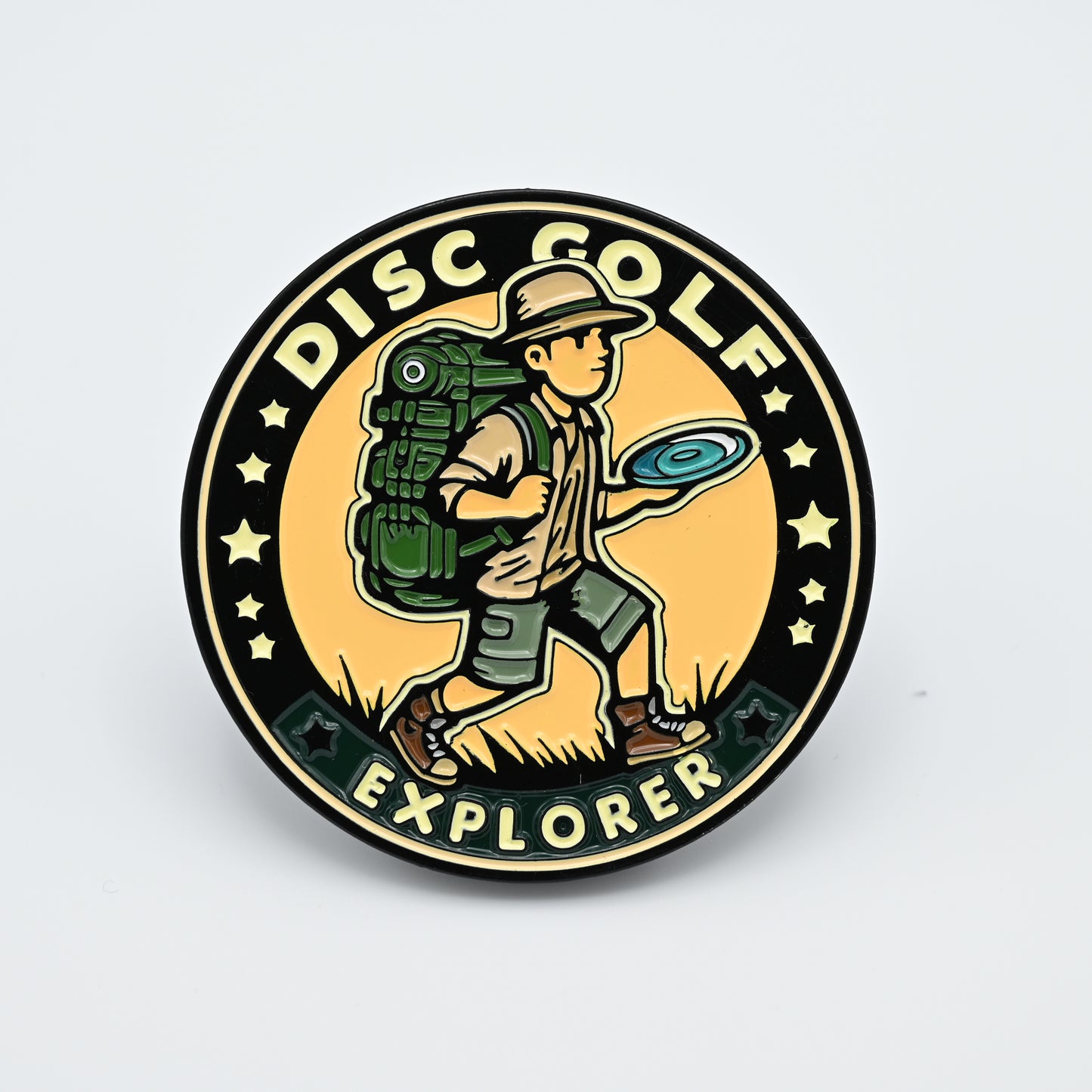 Discgolf pin with a explorer walking around with a discgolf disc in his hand and a backback