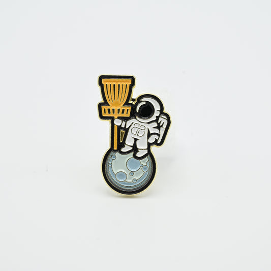 Discgolf pin with a astronaut standing on the moon with a discgolf basket in his right hand.