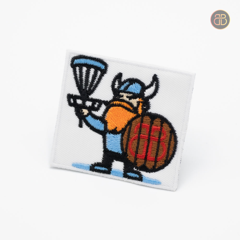 Disc golf patch with a viking holding a discgolf basket with a shield that has the logo of bouncebackdg on it