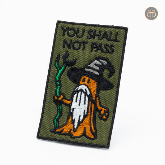 Discgolf patch with the text you shall not pass and a tree holding a stick