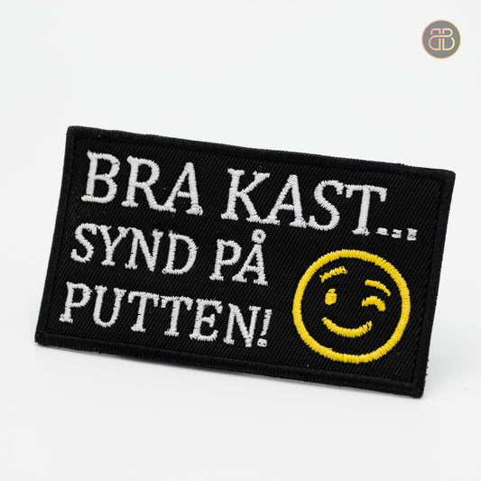 Discgolf patch with the text BRA KAST SYND PÅ PUTTEN and a smiley