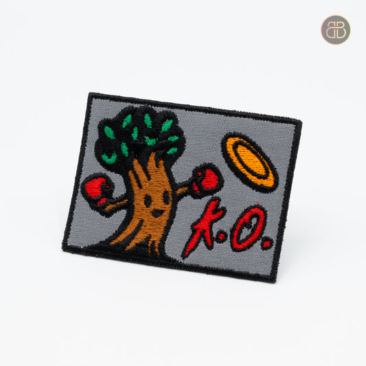 Discgolf patch, a tree hitting a discgolf disc and the text "k.o"